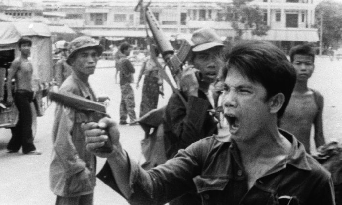 Um soldado do Khmer Vermelho acena com sua pistola e ordena aos donos de lojas que abandonem suas lojas em Phnom Penh, Camboja, em 17 de abril de 1975, quando a capital caiu nas mãos das forças comunistas (AP Photo / Christoph Froehder)
