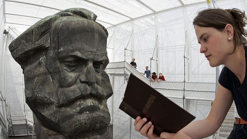 Mulher lê Marx em frente à estátua (UWE MEINHOLD/DDP/AFP via Getty Images)