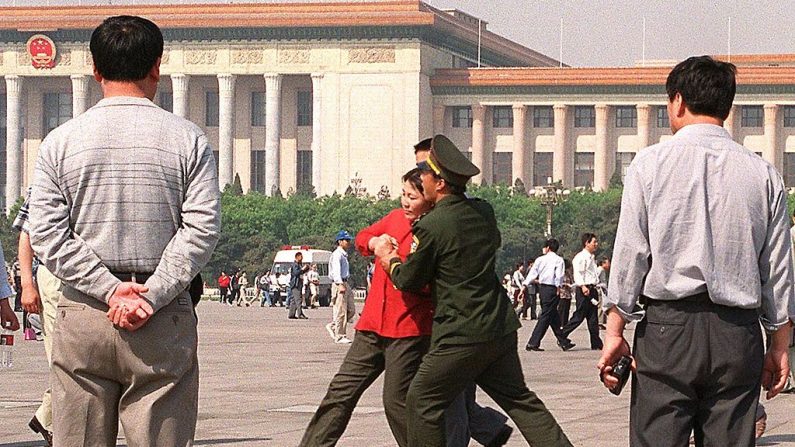 Policiais à paisana assistem a uma praticante do Falun Gong ser levada à força pela polícia para uma van da polícia em 11 de maio de 2000 na Praça Tiananmen de Pequim (STEPHEN SHAVER / AFP via Getty Images)