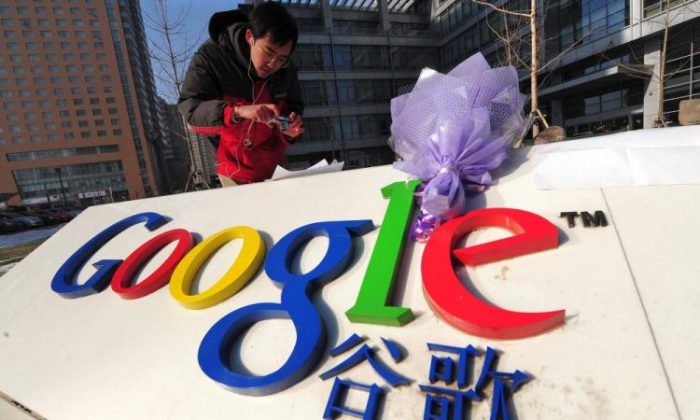 Um buquê de flores estava sobre o logotipo da empresa enquanto um homem fotografava um comentário colocado sob uma rocha do lado de fora da sede do Google China em Pequim em 14 de janeiro de 2010 (Frederic J. Brown / AFP / Getty Images)