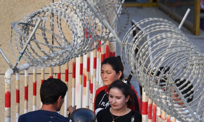 Uma mulher uigur (centro) caminha pela entrada de um bazar em Hotan, região noroeste da China de Xinjiang, em 31 de maio de 2019 (Greg Baker / AFP via Getty Images)
 