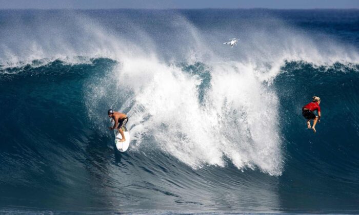 Um surfista pega uma onda enquanto outra é eliminada em Pipeline, na costa norte de Oahu, Havaí, em 14 de fevereiro de 2021 (Brian Bielmann / AFP via Getty Images)
