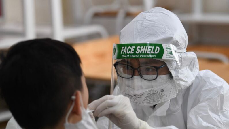 Um trabalhador de saúde com equipamento de proteção individual (PPE) realiza um teste de cotonete COVID-19 em um aluno da escola particular Vinschool em Hanói, Vietnã, em 22 de maio de 2021 (Nhac Nguyen / AFP via Getty Images)
 