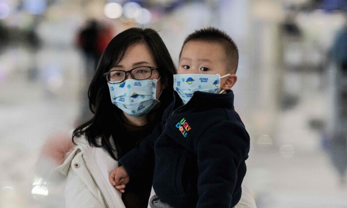 Uma mulher e uma criança usando máscaras de proteção caminham até os balcões de check-in no Aeroporto Internacional de Daxing, em Pequim, em 21 de janeiro de 2020 (Nicolas Asfouri / AFP via Getty Images)
 