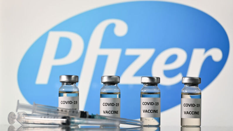 Frascos com etiquetas adesivas que dizem "vacina COVID-19" e seringas ao lado do logotipo da farmacêutica norte-americana Pfizer (Justin Tallis / AFP x Getty Imíaages)
 