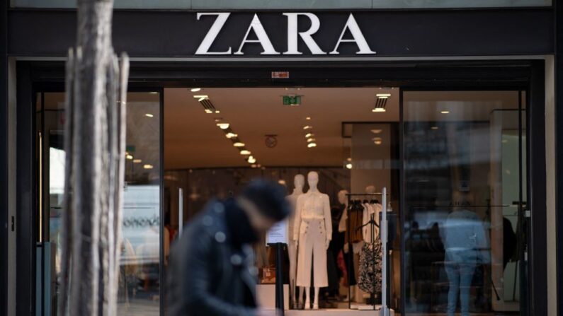 Um homem está sentado em frente a uma loja de pronto-a-vestir Zara no centro de Nantes, oeste da França, em 25 de março de 2021. (Loic Venance / AFP via Getty Images)
 