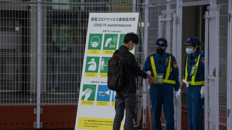 Um homem mede sua temperatura por um segurança ao entrar no Centro de Imprensa Principal dos Jogos Olímpicos de Tóquio (MPC) em 2 de julho de 2021 em Tóquio, Japão (Carl Court / Getty Images)
 