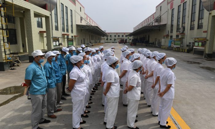 Trabalhadores fizeram fila para cantar canções "vermelhas" comunistas em uma fábrica de macarrão instantâneo, perto da vila na província de Henan, na China, em 29 de setembro de 2017. Recentemente, o Partido Comunista Chinês estendeu ainda mais seu controle sobre empresas privadas e estrangeiras. propriedade, com filiais partidárias (Greg Baker / AFP / Getty Images)
