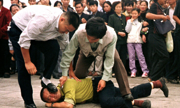 Dois policiais à paisana prendem um praticante do Falun Gong na Praça Tiananmen, em Pequim, em 31 de dezembro de 2000 (Chien-min Chung / AP Photo)
