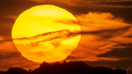 Fotógrafo captura uma visão surreal do enorme pôr do sol por trás de uma formação rochosa icônica no Reino Unido