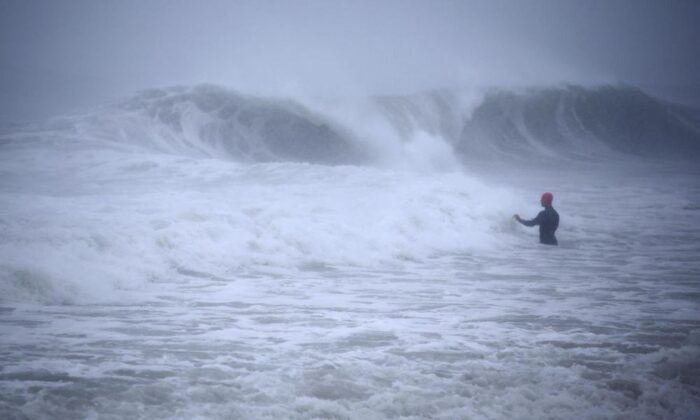 Matt Prue, de Stonington, Connecticut, caminha para o Oceano Atlântico para surfar nas ondas da tempestade tropical Henri conforme ela se aproxima de Westerly, RI, em 22 de agosto de 2021.(Stew Milne / AP Photo)
