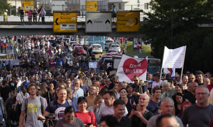 Pessoas marcham por uma rua durante um protesto contra as medidas COVID-19 impostas pelo governo em Ljubljana, Eslovênia, em 29 de setembro de 2021 (Darko Bandic / AP Photo)
