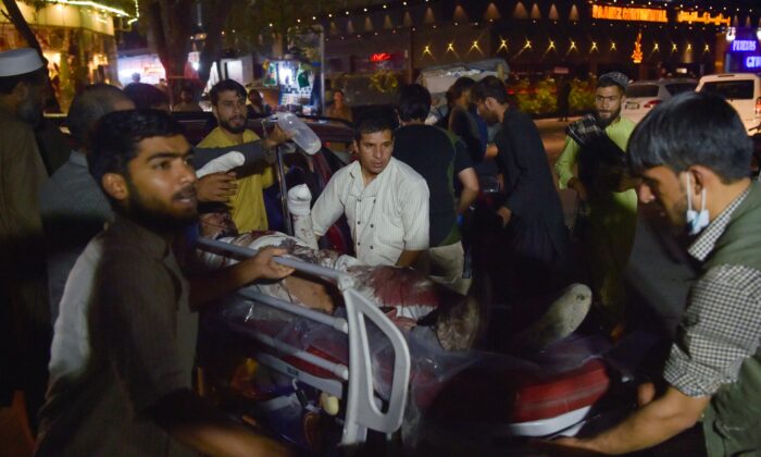 Voluntários e equipe médica carregam um homem ferido para um hospital em Cabul após as explosões do lado de fora do aeroporto Hamid Karzai, no Afeganistão, em 26 de agosto de 2021 (Wakil Kohsar / AFP via Getty Images)
