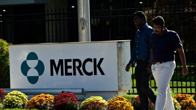 Os funcionários passam por uma placa da Merck em frente ao prédio da empresa em 2 de outubro de 2013 em Summit, NJ (Kena Betancur / Getty Images)
