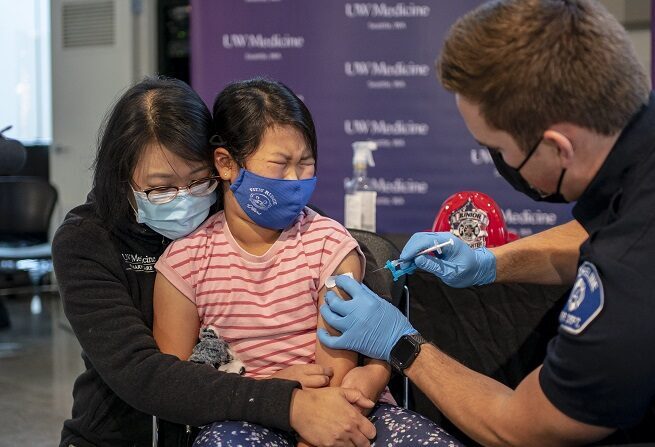 Elise Wong, 7, senta-se no colo de sua mãe, Crystal Wong, enquanto recebe a vacina COVID-19 da Pfizer-BioNtech em 3 de novembro de 2021, em Shoreline, Washington (David Ryder / Getty Images)