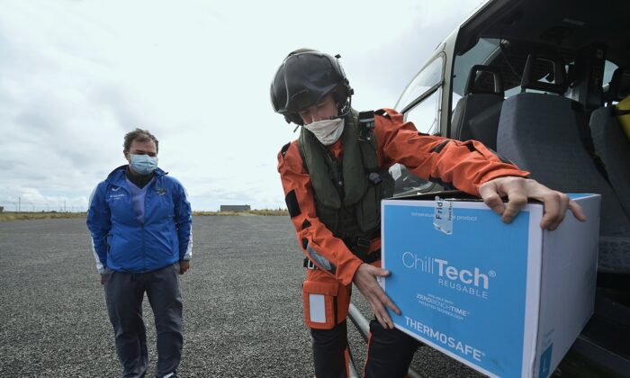 Dr. Alex Michel recebe vacinas contra a COVID-19 de um membro da tripulação do Irish Air Corps, enquanto as forças militares ajudam com vacinações em ilhas remotas, em Inishbofin, Irlanda, no dia 18 de maio de 2021 (Charles McQuillan / Getty Images)
