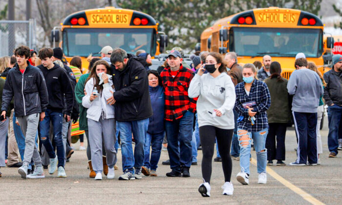 Pais saem com seus filhos do estacionamento da Meijer, onde muitos alunos se reuniram após uma situação de atirador ativo na Oxford High School em Oxford, no estado de Michigan, no dia 30 de novembro de 2021 (Eric Seals / USA TODAY NETWORK via Reuters)