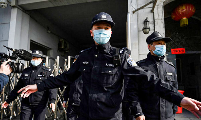 Policiais protegem uma entrada lateral após a chegada de veículos da polícia no Tribunal Popular Intermediário de Dandong, na província de Liaoning, no nordeste da China, no dia 19 de março de 2021 (Noel Celis / AFP via Getty Images)