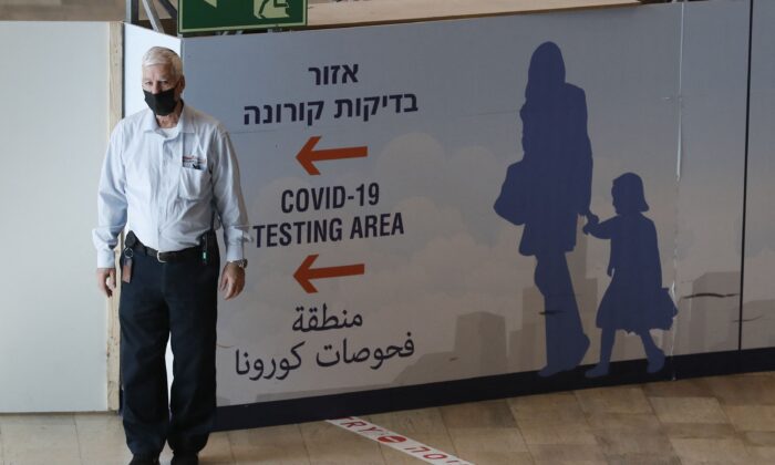 Membro da equipe auxilia os passageiros que chegam no Aeroporto Ben Gurion de Israel em Lod, a leste de Tel Aviv, no dia 28 de novembro de 2021 (Ahmad Gharabli / AFP via Getty Images)