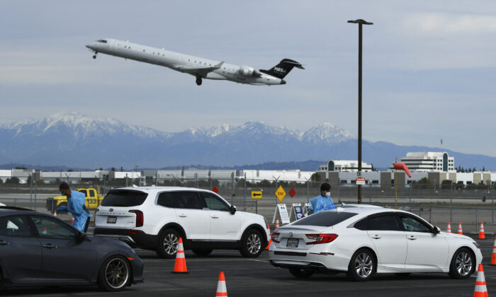 Uma aeronave Mesa Airlines CRJ-900 decola do Aeroporto Internacional de Long Beach (LGB) enquanto as pessoas recebem testes de PCR para COVID-19 em um local de testes do Departamento de Saúde de Long Beach no estacionamento de uma antiga fábrica de aeronaves da Boeing, em Long Beach, na Califórnia, no dia 10 de janeiro de 2022 (Patrick T. Fallon/AFP via Getty Images)