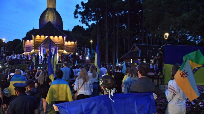 Membros da comunidade ucraniana com bandeiras nacionais participam de protesto contra a guerra e em apoio à Ucrânia no Memorial Ucraniano em Curitiba, Paraná, Brasil, no dia 25 de fevereiro de 2022 (NELSON ALMEIDA/AFP via Getty Images)
