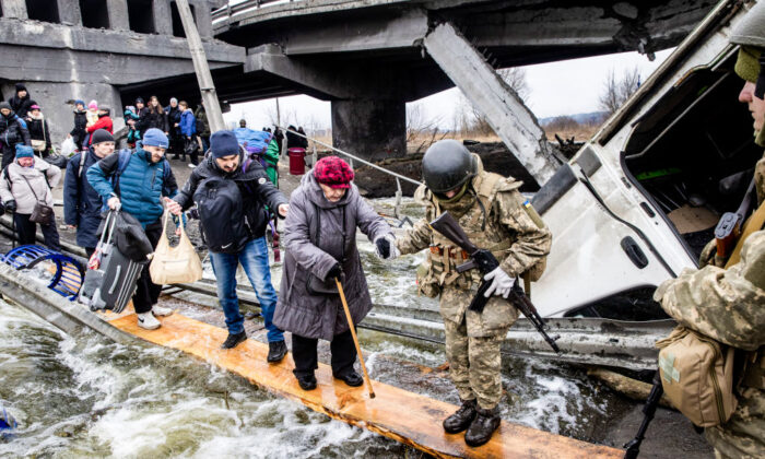 Moradores de Irpin, na Ucrânia, fogem de combates intensos por meio de uma ponte destruída quando as forças russas entraram na cidade no dia 7 de março de 2022 (Chris McGrath/Getty Images)