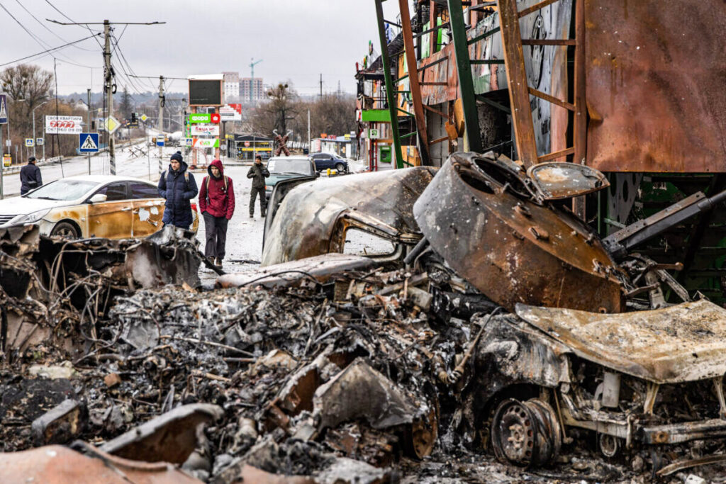 Pessoas passam por um veículo militar russo destruído em uma posição de linha de frente em Irpin, Ucrânia, no dia 3 de março de 2022 (Chris McGrath/Getty Images)