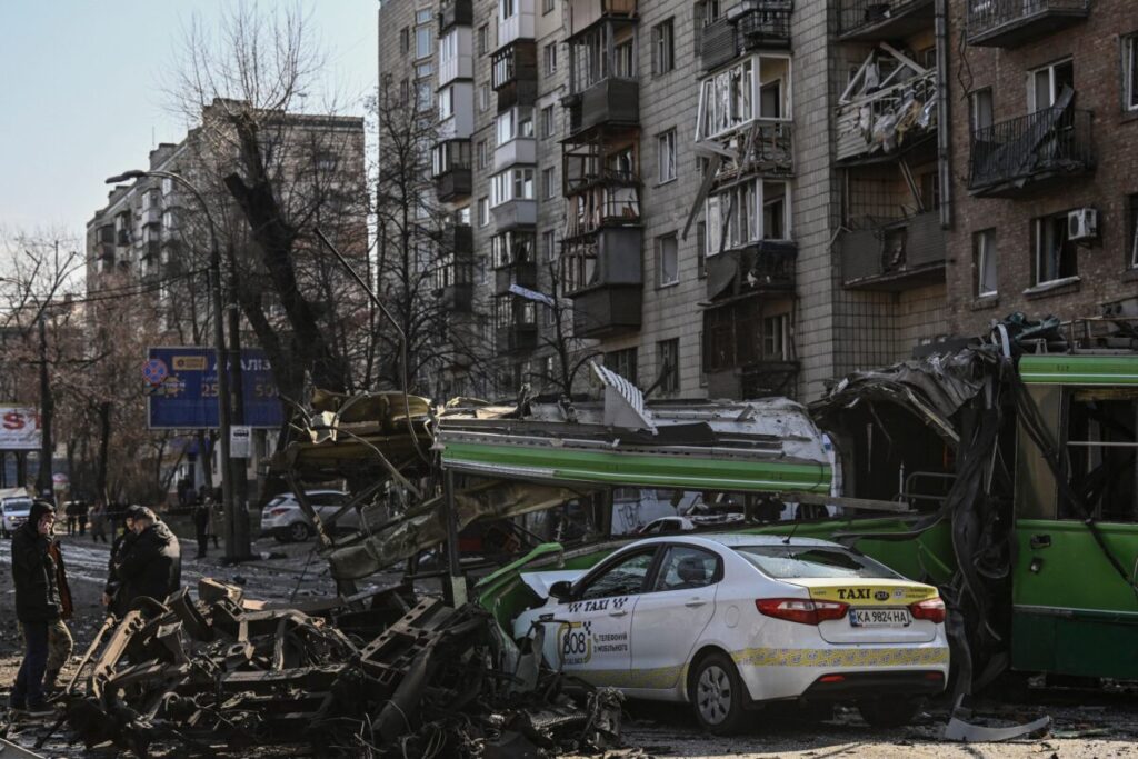 Um militar ucraniano (E) caminha em frente a um prédio de apartamentos destruídos após bombardeio, em Kiev, na Ucrânia, no dia 14 de março de 2022 (Aris Messinis/AFP via Getty Images)