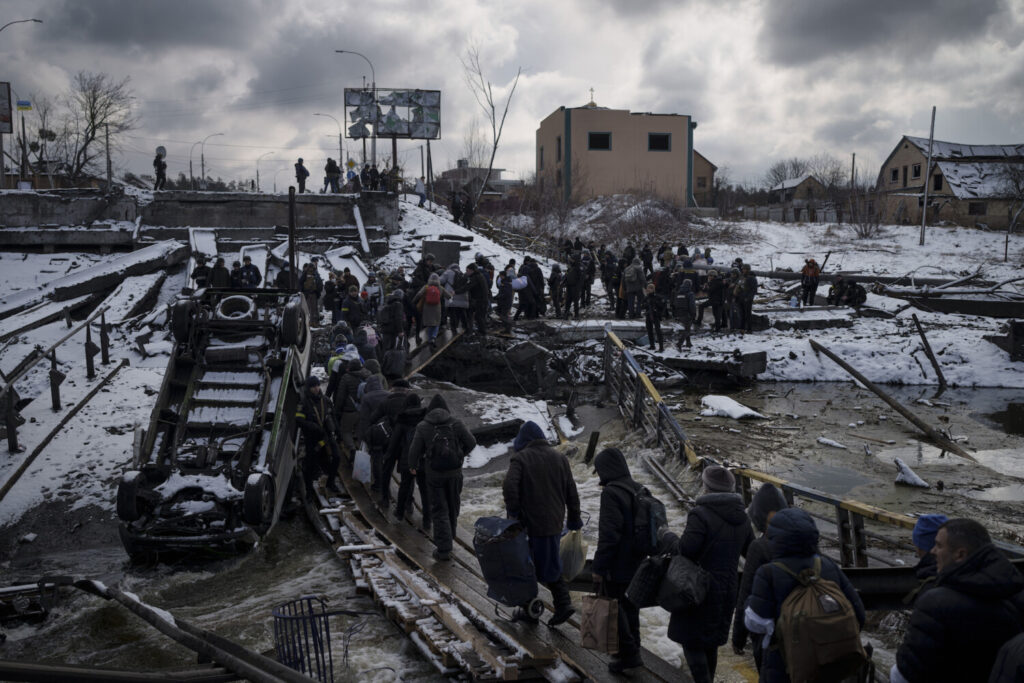 Ucranianos cruzam um caminho improvisado sob uma ponte destruída enquanto fogem de Irpin, nos arredores de Kiev, na Ucrânia, no dia 8 de março de 2022 (Felipe Dana/AP Photo)