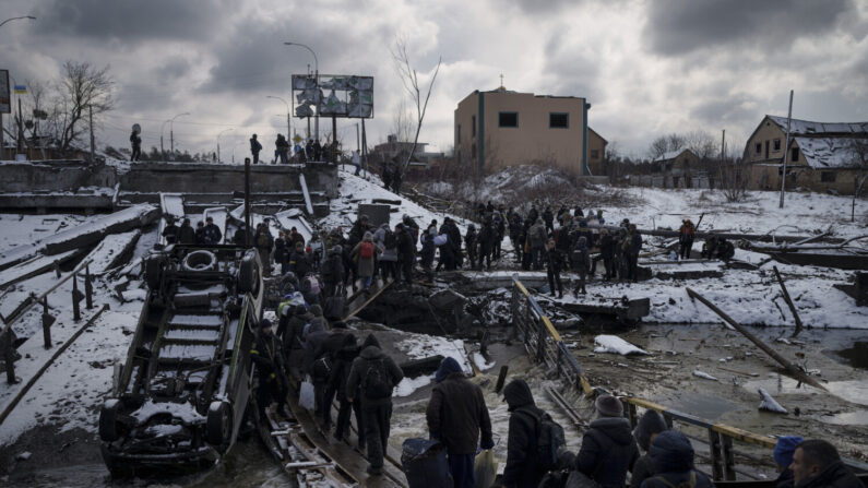 Ucranianos cruzam um caminho improvisado sob uma ponte destruída enquanto fogem de Irpin, nos arredores de Kiev, na Ucrânia, no dia 8 de março de 2022 (Felipe Dana/AP Photo)