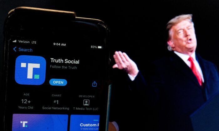 Uma imagem do ex-presidente Donald Trump ao lado de uma tela de telefone que exibe o aplicativo Truth Social em Washington, em 21 de fevereiro de 2022 (Stefani Reynolds/AFP via Getty Images)