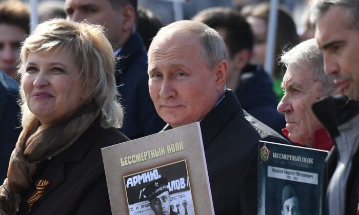 O presidente russo Vladimir Putin e outros participantes carregam retratos de seus parentes no centro de Moscou em 9 de maio de 2022 (Natalia Kolesnikova/AFP via Getty Images)