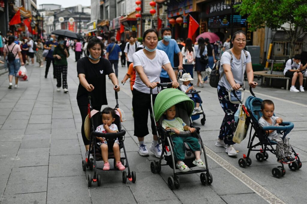 Pessoas empurram carrinhos de bebê por uma rua comercial em Pequim, em 13 de julho de 2021 (Wang Zhao/AFP via Getty Images)