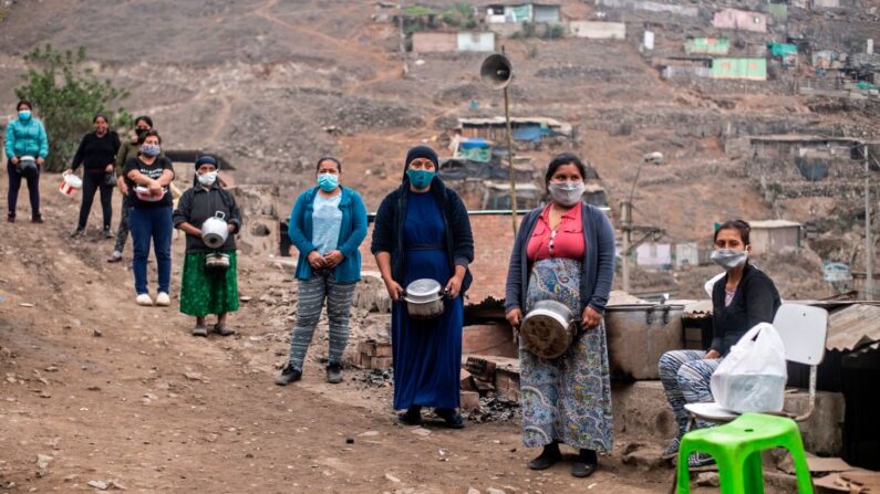 Mulheres mantêm distâncias de segurança enquanto esperam para conseguir comida em um refeitório do setor de Pamplona Alta -que também sofre com falta de água- nos arredores do sul de Lima em 28 de maio de 2020, durante a pandemia do novo coronavírus (Foto de ERNESTO BENAVIDES/AFP via Getty Images)