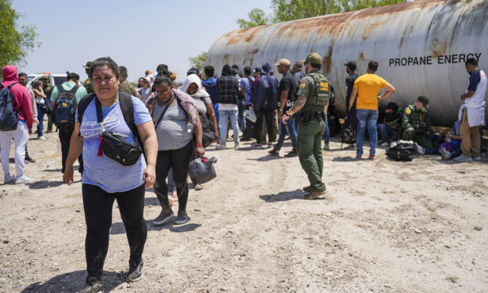 Um agente da Patrulha da Fronteira organiza um grande grupo de imigrantes ilegais perto de Eagle Pass, Texas, em 20 de maio de 2022 (Charlotte Cuthbertson/The Epoch Times)