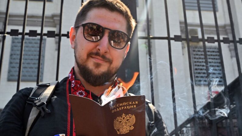 Um cidadão russo segura seu passaporte em chamas do lado de fora da embaixada russa na capital ucraniana de Kyiv em 12 de junho de 2022, durante um 'protesto-performance' em meio à invasão russa da Ucrânia (Foto de SERGEI SUPINSKY/AFP via Getty Images)