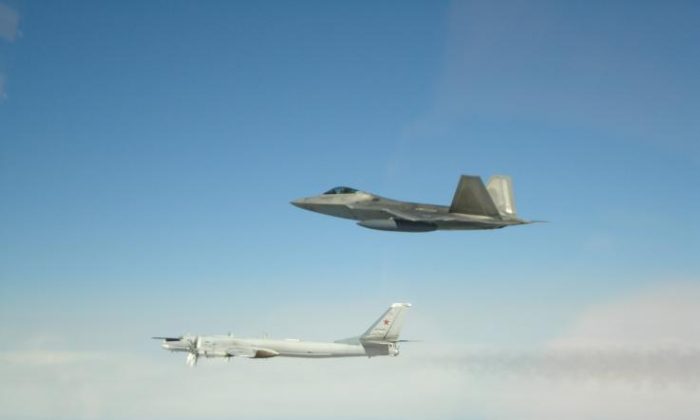 Um bombardeiro estratégico e porta-mísseis russo Tupolev Tu-95 (L) é visto sendo acompanhado por um caça F-22 dos EUA no espaço aéreo internacional na costa do Alasca em uma foto de arquivo (NORAD)