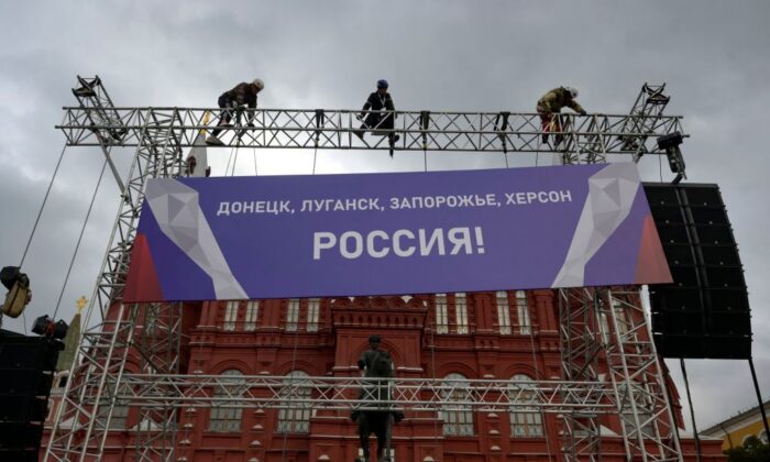 Trabalhadores fixam uma faixa com os dizeres "Donetsk, Lugansk, Zaporizhzhia, Kherson — Rússia!" no topo de uma construção instalada em frente ao Museu Histórico do Estado, fora da Praça Vermelha, no centro de Moscou, em 29 de setembro de 2022 (Natalia Kolesnikova/AFP via Getty Images)
