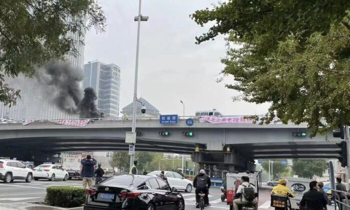 Pessoas tiram fotos de banners raros de protesto político de um viaduto em Pequim, em 13 de outubro de 2022 (Captura de tela da conta de Fangshimin no Twitter via The Epoch Times)