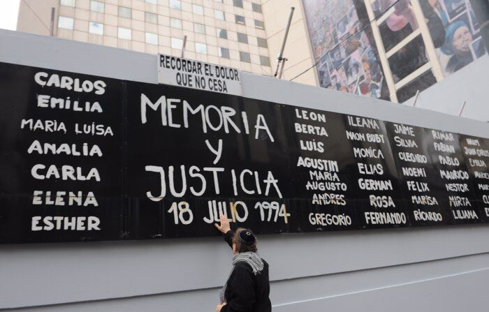 Um homem toca um cartaz com os nomes das vítimas durante um ato comemorativo do ataque contra a mutualidade judaica AMIA, em uma fotografia de arquivo (EFE/Enrique G. Medina)