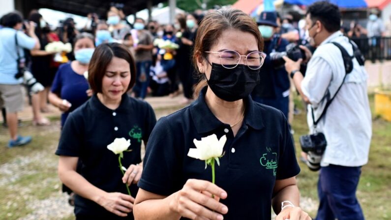 Mulheres seguram rosas brancas para colocar nos degraus da creche, onde um ex-policial matou pelo menos 37 pessoas em um tiroteio em massa, em Na Klang, na província de Nong Bua Lam Phu, nordeste da Tailândia, em 7 de outubro de 2022 (Foto de Manan VATSYAYANA/AFP) (Foto de MANAN VATSYAYANA/AFP via Getty Images)