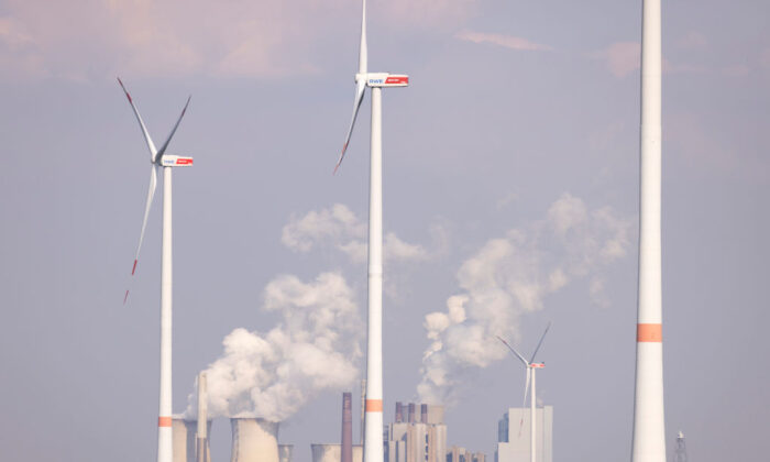 O vapor sobe das torres de resfriamento da usina a carvão Neurath enquanto as turbinas eólicas giram sobre um campo de colza perto de Bedburg, na Alemanha, em 05 de maio de 2022 (Andreas Rentz/Getty Images)
