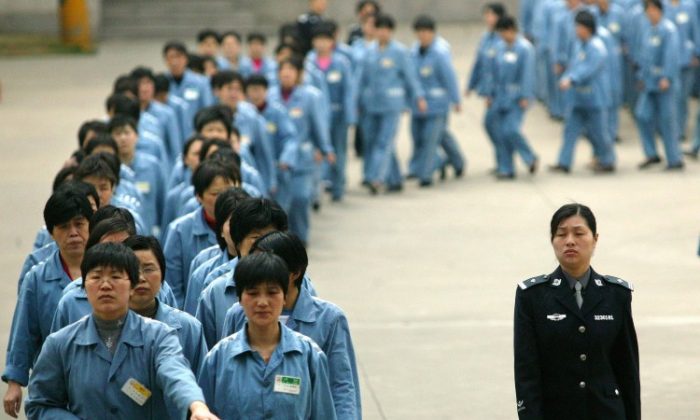 Prisioneiros caminham ao lado de uma escolta policial durante um dia aberto na prisão em Nanjing, China, em 11 de abril de 200. (STR/AFP/Getty Images)