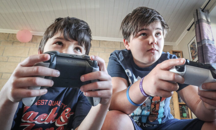 Dois meninos brincando com um console de videogame XBox em Vezin, Bélgica, em 26 de março de 2020 (Bruno Fahy/Belga Mag/AFP via Getty Images)