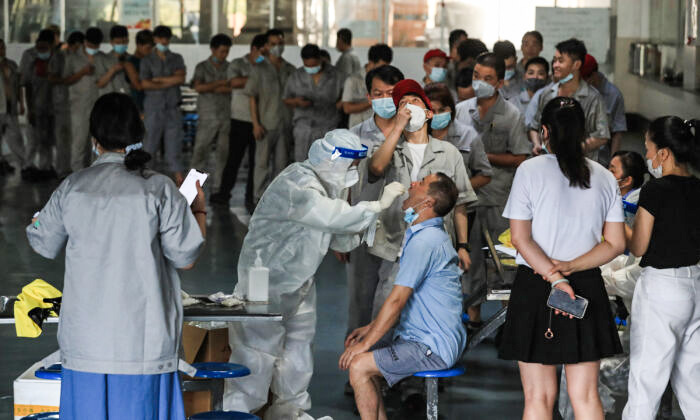 Um realiza um teste de COVID-19 no refeitório de uma fábrica de autopeças em Wuhan, província de Hubei, centro da China, em 4 de agosto de 2021 (STR/AFP via Getty Images)
