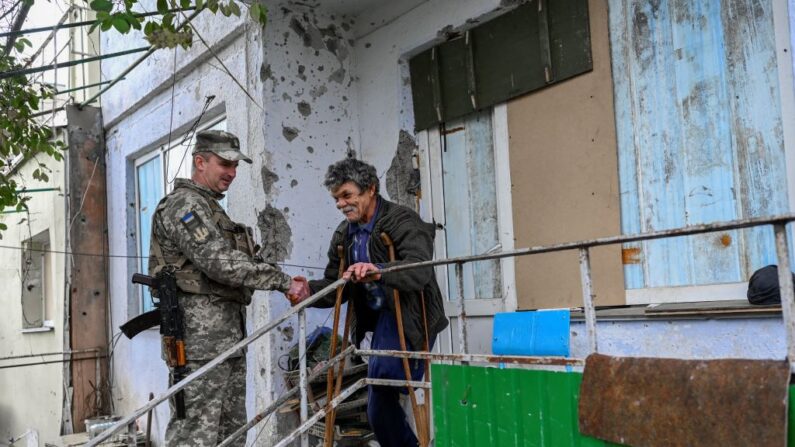 Um soldado ucraniano conversa com um civil na vila fronteiriça de Kherson, nos arredores de Mykolaiv, em 31 de outubro de 2022 (Foto de BULENT KILIC/AFP via Getty Images)