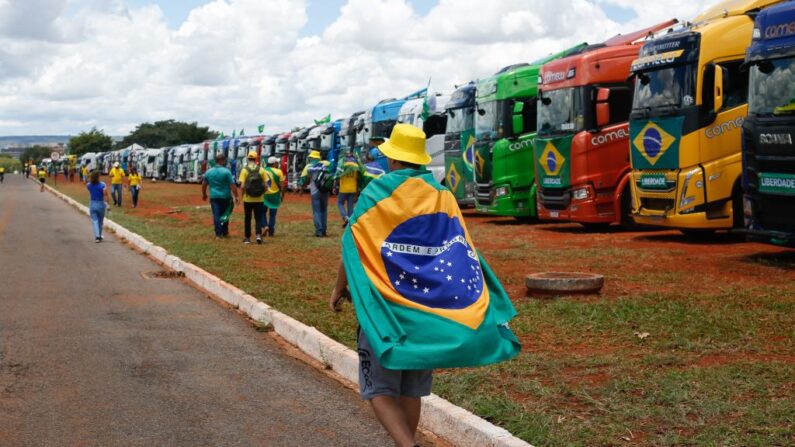 Manifestante caminha em frente aos caminhões durante manifestação em Brasília, em 13 de novembro de 2022 (Foto de SERGIO LIMA/AFP via Getty Images)