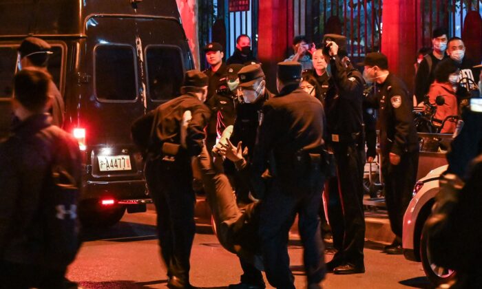 Um homem é preso enquanto manifestantes se reuniam em uma rua em Xangai em 27 de novembro de 2022. Protestos contra a política 'COVID-zero' da China ocorreram na noite anterior após um incêndio mortal em Urumqi, capital da região de Xinjiang. (Hector Retamal/AFP via Getty Images)