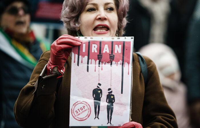 Uma mulher segura um cartaz durante um comício contra as execuções de manifestantes no Irã, em Berlim, Alemanha, 10 de dezembro de 2022 (EFE/EPA/CLEMENS BILAN)