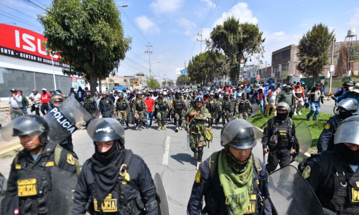 Membros da polícia escoltam apoiadores do ex-presidente Pedro Castillo enquanto marcham até o centro da cidade de Arequipa, no Peru, exigindo o fechamento do Congresso e a libertação de Castillo, em 14 de dezembro de 2022. (Diego Ramos/AFP via Getty Imagens)